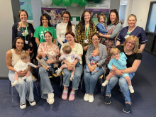 New Parents, babies, Hartlepool staff and staff from other organisations smiling at the camera at Hartlepool's first Birthday celebration. Behind them are NCT banners and balloons